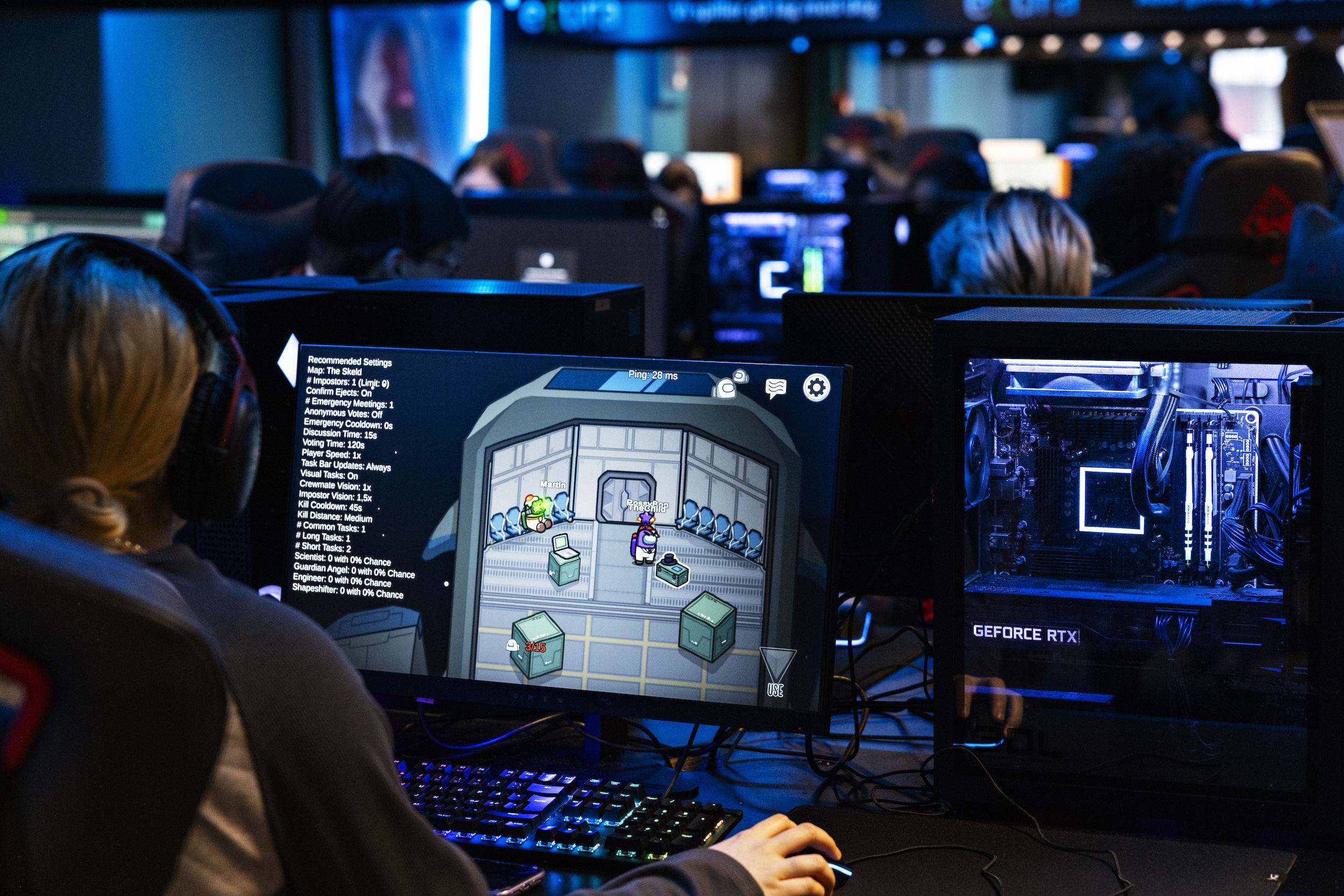Ryggen på en ungdom som sitter på en skjerm og gamer. Foran henne sitter mange andre ungdommer og gjør det samme. 