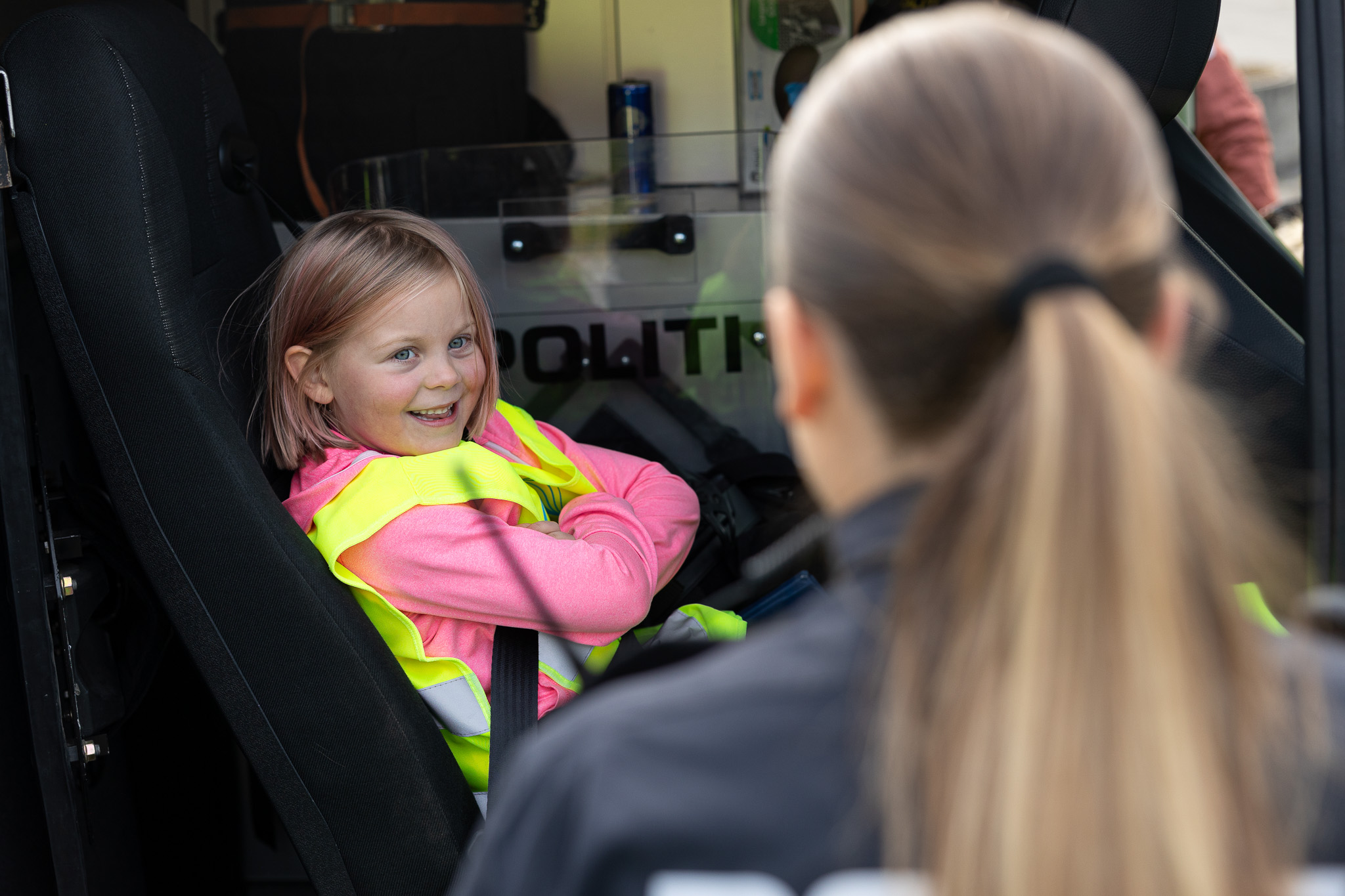 jente med refleksvest sitter inne i en politibil