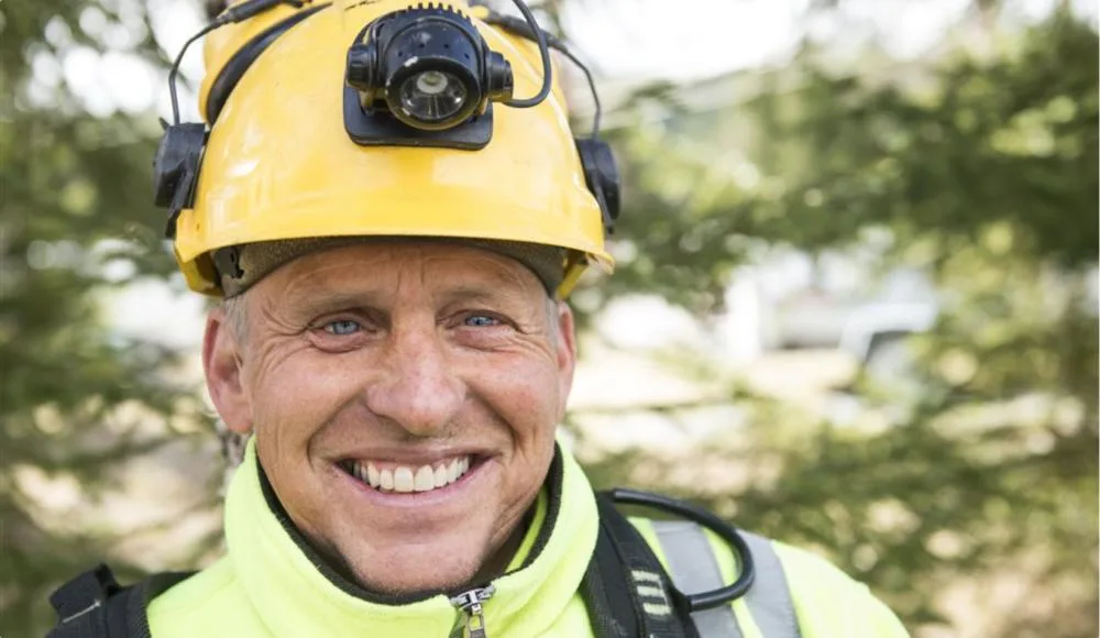 NTE-montør med hjelm smiler mot kamera NTE-montør med hjelm smiler mot kamera