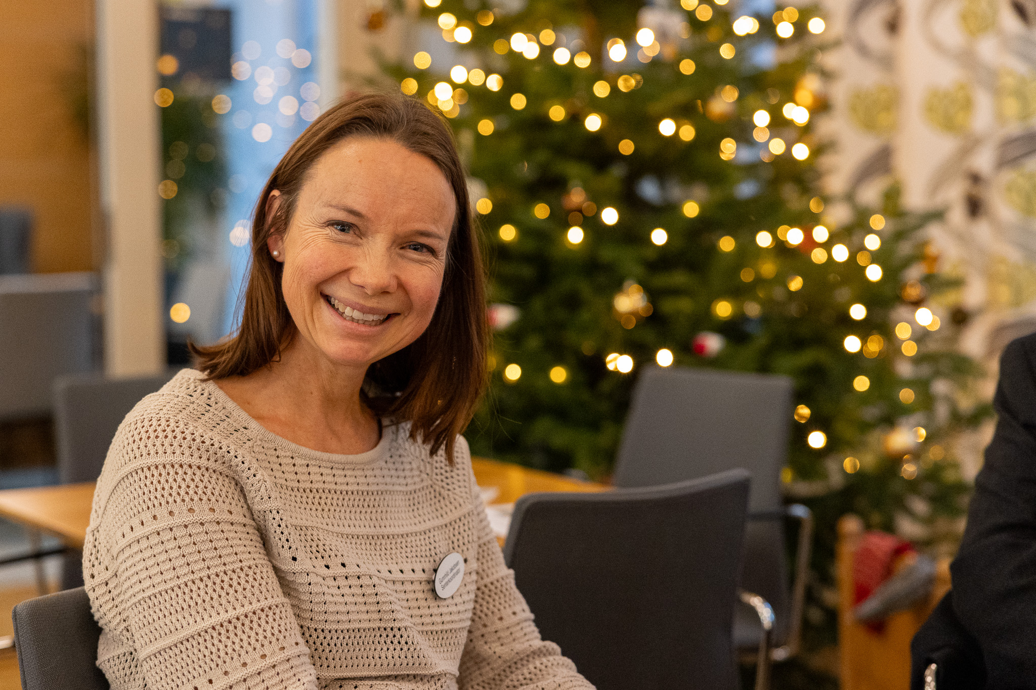 Smilende kvinne foran et juletre
