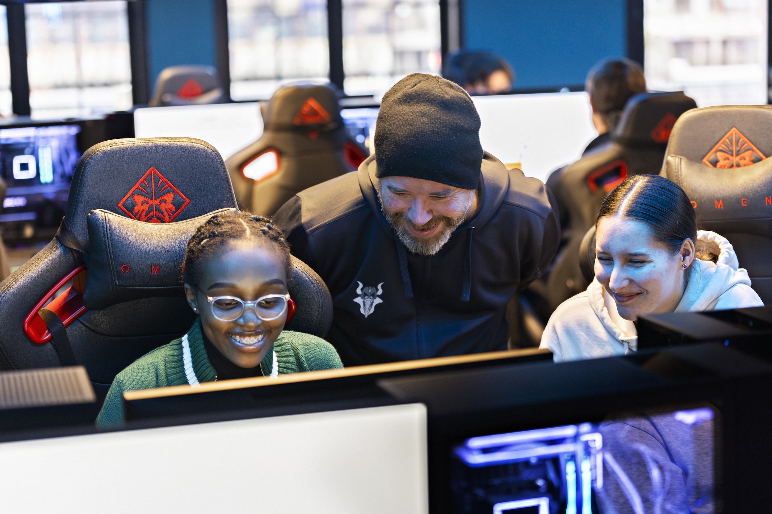 En smilende mann står mellom to glade jenter som gamer