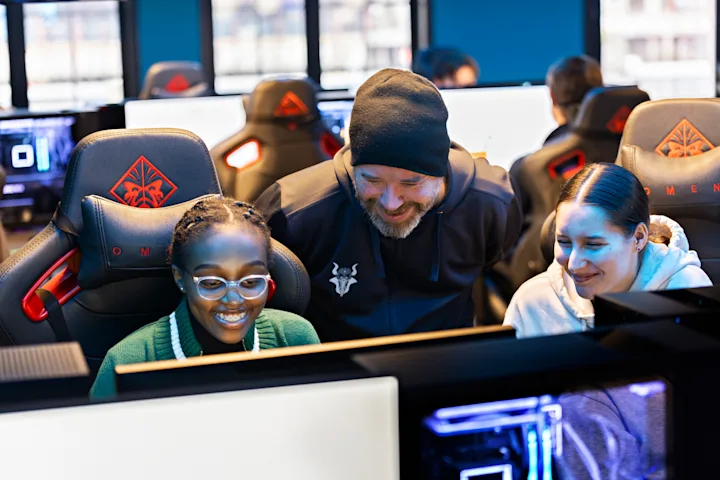 En smilende mann står mellom to glade jenter som gamer En smilende mann står mellom to glade jenter som gamer
