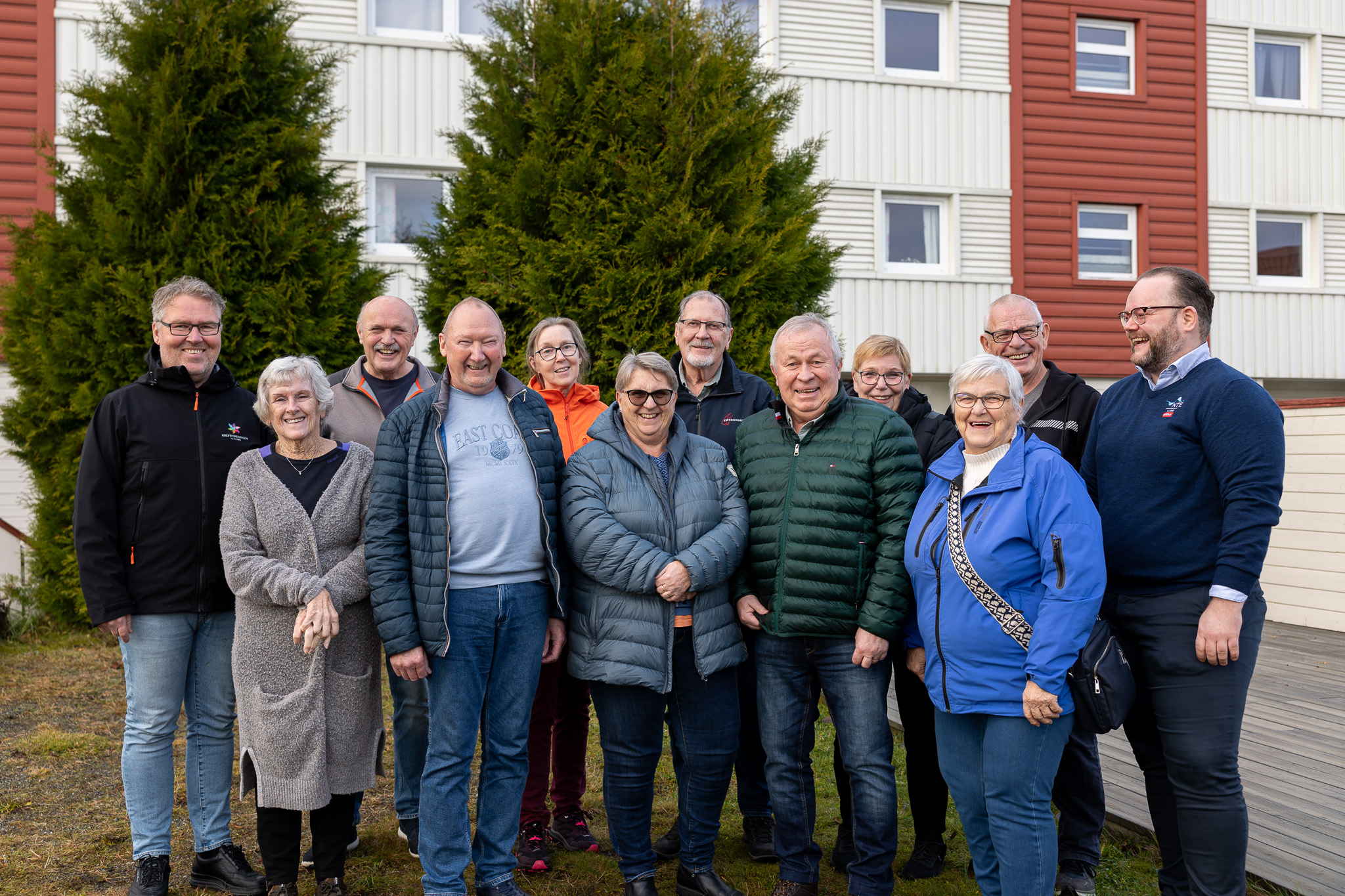 12 blide mennesker utenfor en blokk