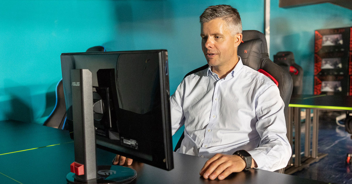 Mann i skjorte sitter bak en skjerm og spiller dataspill