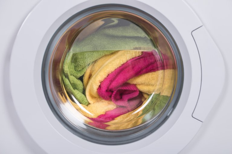 Vaskemaskin med gule, rosa og grønne håndduker