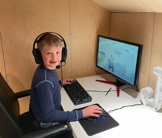 Gutt sitter foran pc-skjerm med hodetelefoner og spiller dataspill Gutt sitter foran pc-skjerm med hodetelefoner og spiller dataspill