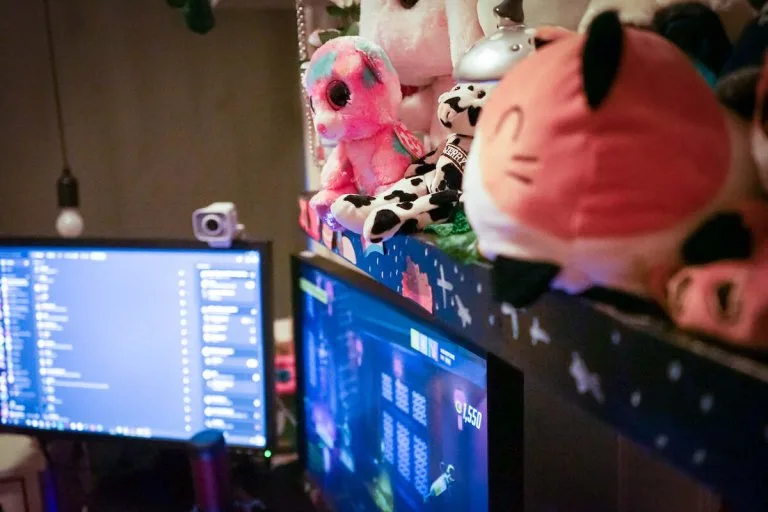kosedyr og gaming Flere kosedyr på en hylle over to dataskjermer