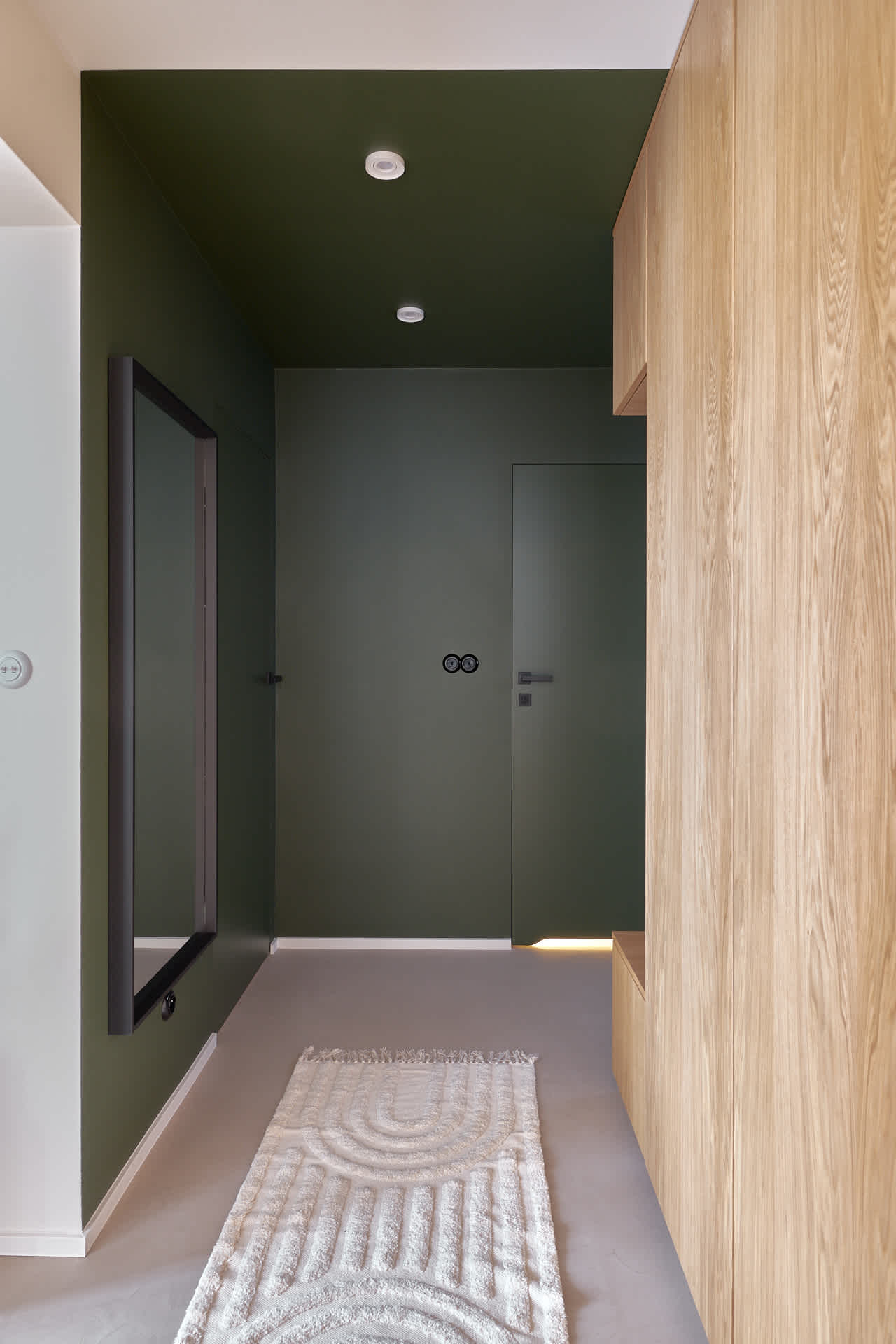 Wyraźny kontrast kolorystyczny między jednym fragmentem mieszkania a drugim pomaga wydzielić przestrzenie o różnych funkcjach i podkreśla samą architekturę wnętrza. Użycie ciemnej farby w niepozornej przestrzeni, w tym także na suficie, tworzy w korytarzu kameralną atmosferę | projekt: Kamiko