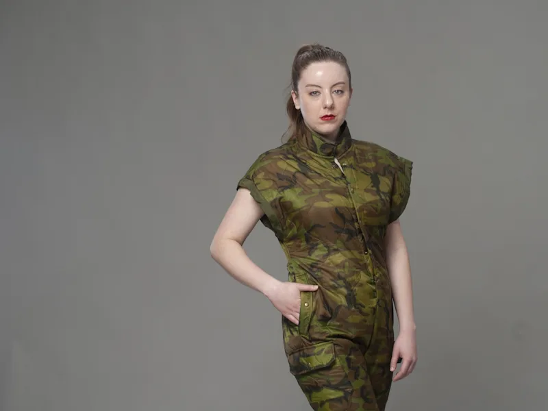 Studio portrait in camouflage uniform with hand on hip against neutral gray backdrop