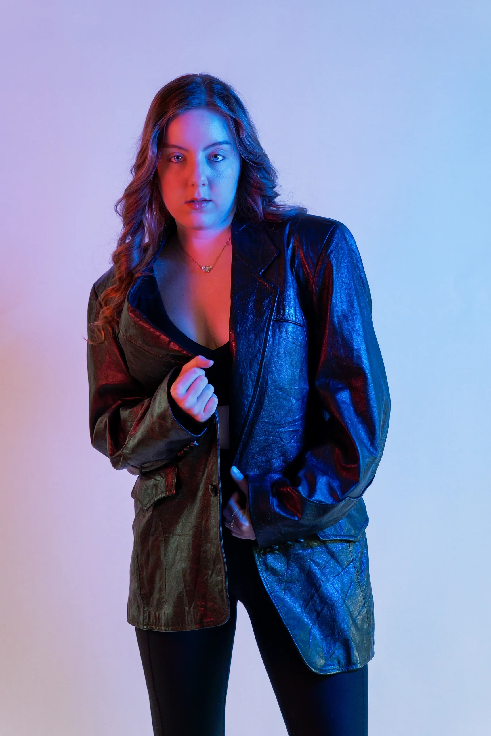 Studio portrait with dramatic red and blue split gel lighting, black leather jacket, direct gaze