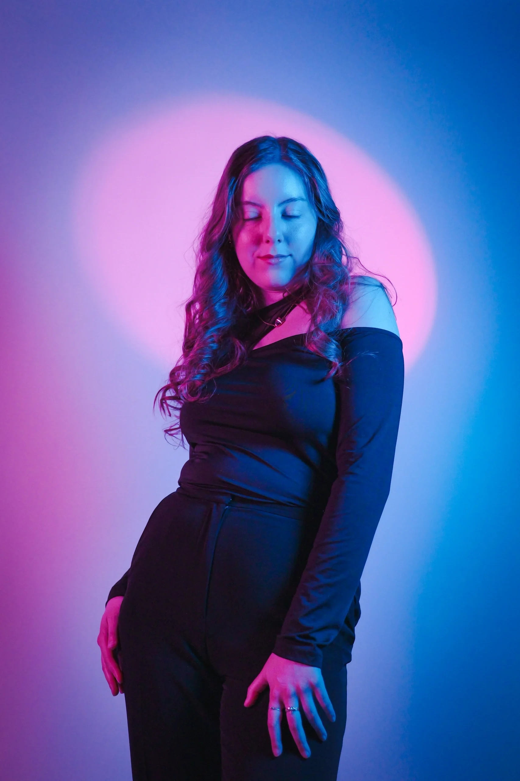 Tranquil pose with eyes closed, black off-shoulder outfit, magenta-cyan split lighting and halo