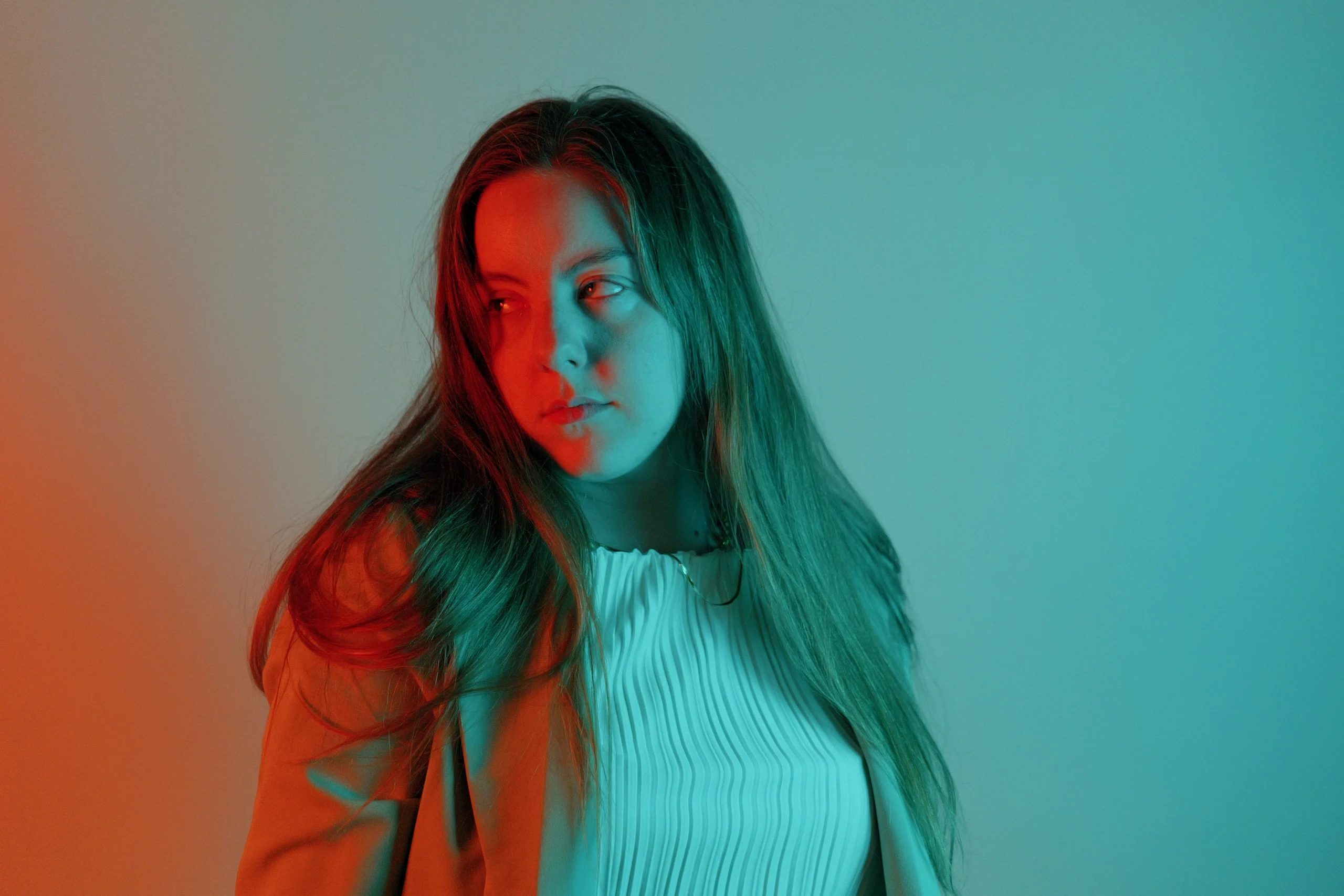 Three-quarter pose in white ribbed top with orange and cyan split gel lighting