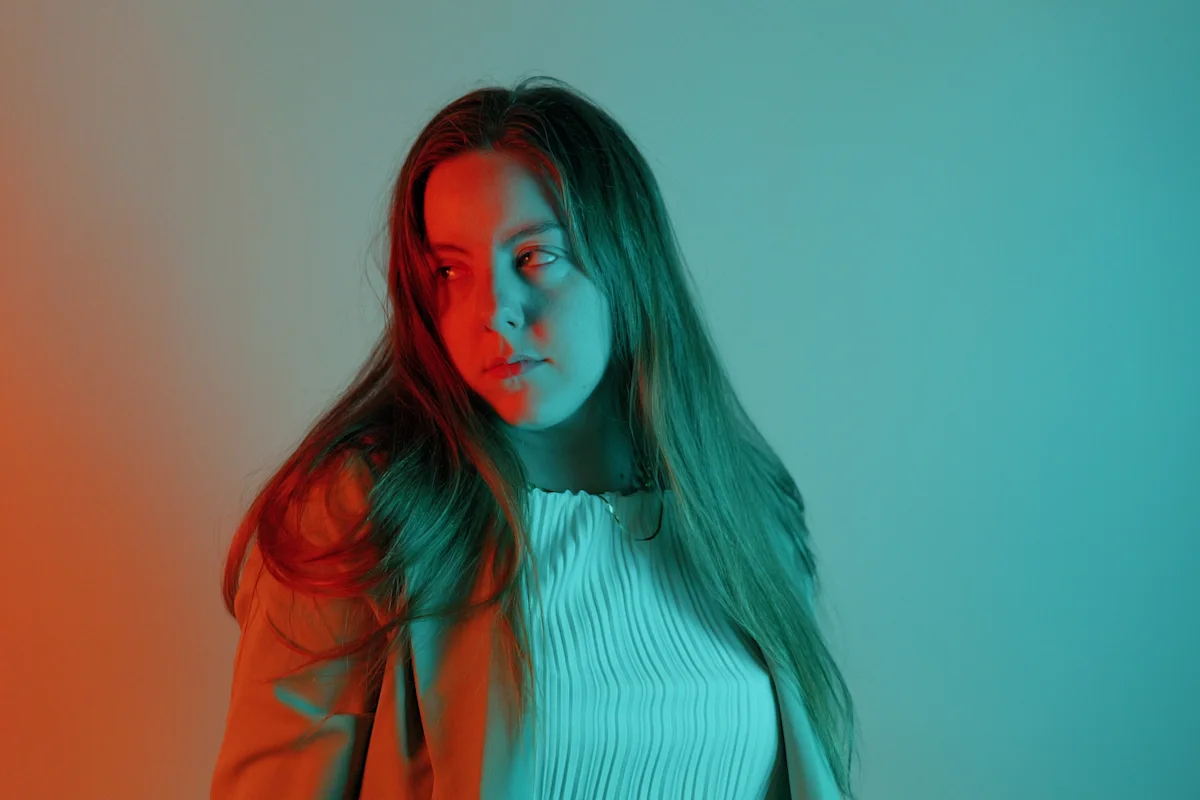 Three-quarter pose in white ribbed top with orange and cyan split gel lighting