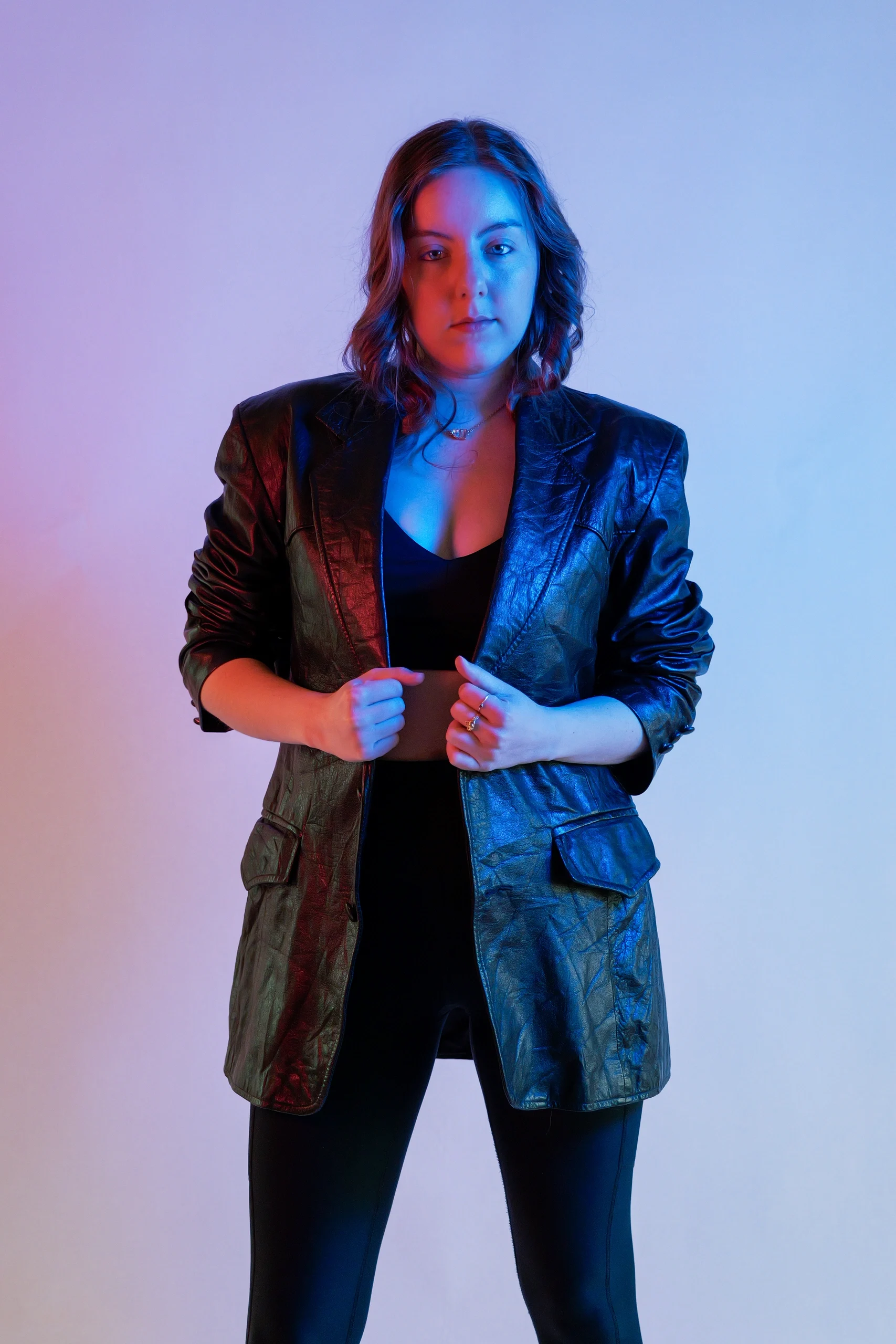 Editorial portrait with split gel lighting, black leather jacket, and confident frontal pose