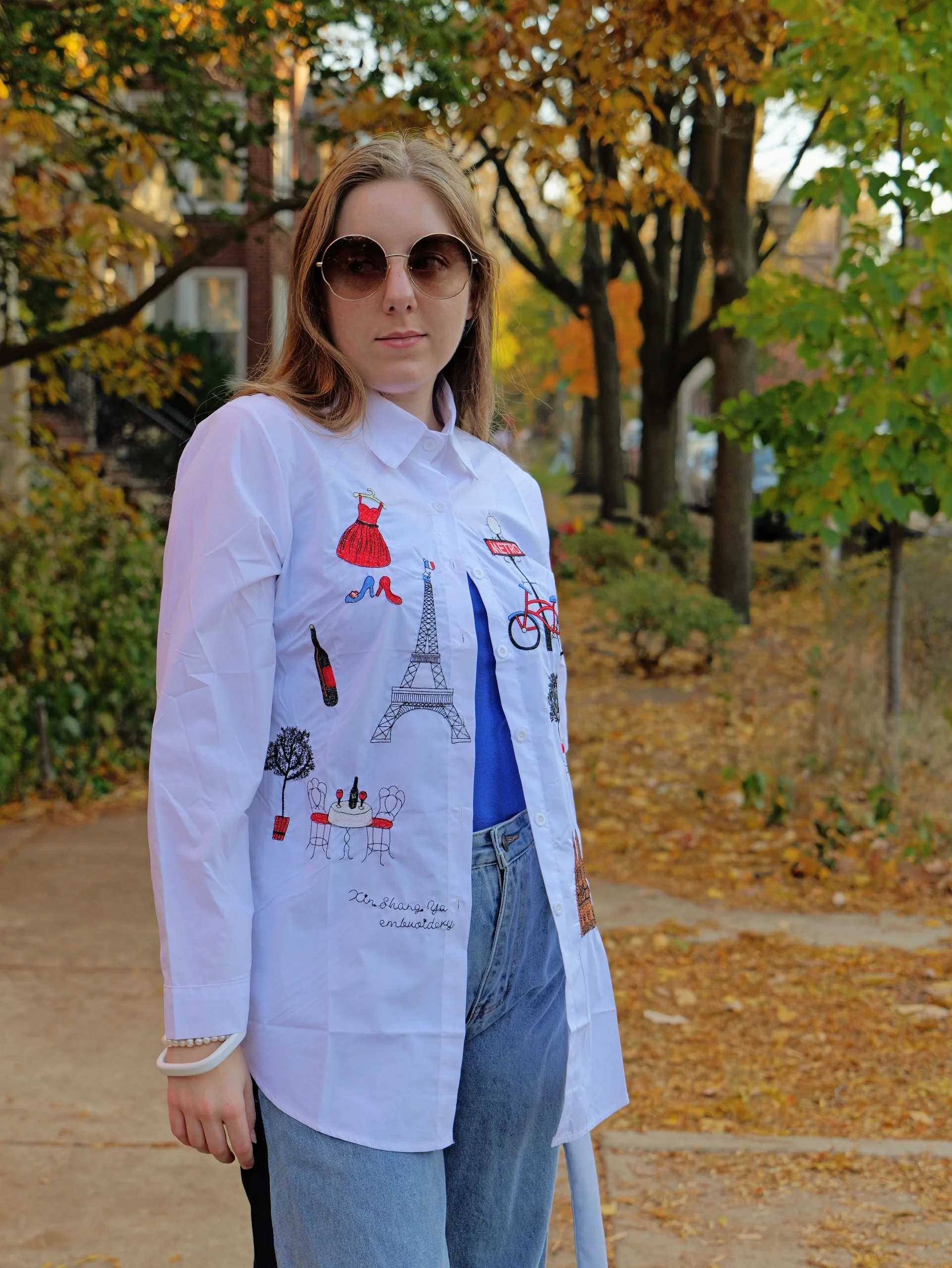 Lifestyle portrait with Parisian embroidered shirt and sunglasses in autumn park setting