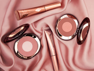 Two, open, duo blush compacts with mirrored-lids in rose gold and champagne and medium-pink and rosy-brown with two highlighter blush wands in rose gold and medium-pink.