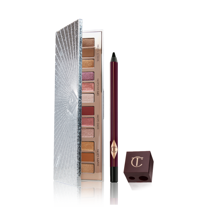 An open eyeshadow palette with twelve eyeshadows in matte and shimmery shades in pink, purple, red, gold, brown, and cream, an eyeliner pencil in black, and a lip and eye pencil sharpener. 