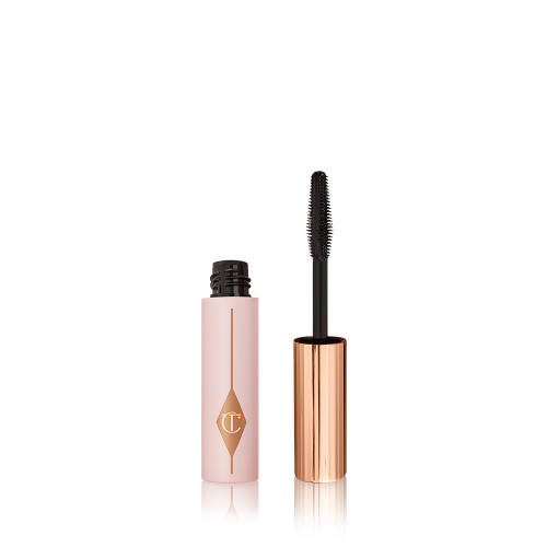 Travel-size mascara in a pink-coloured tube with its gold-coloured applicator next to it. 