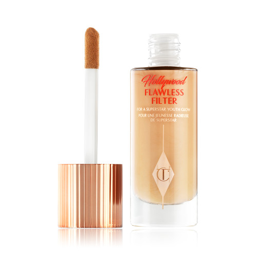 An open glow-boosting primer in a glass bottle with a rose gold-coloured lid with a doe-foot applicator.