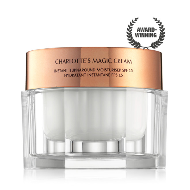 Pearly-white face cream in a glass jar with a gold-coloured lid with text on it, 'Charlotte's magic cream'.