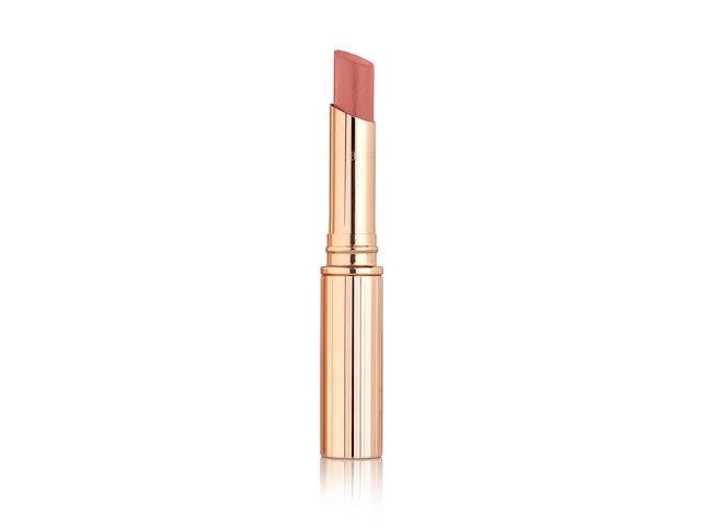 An open sheer, glittering lipstick in a bronze coral-pink shade in golden packaging. 