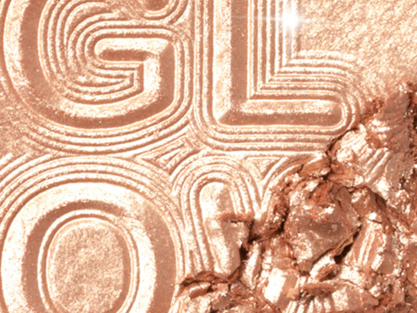 Close-up of a powder highlighter in a warm-tone, light-medium gold colour. 