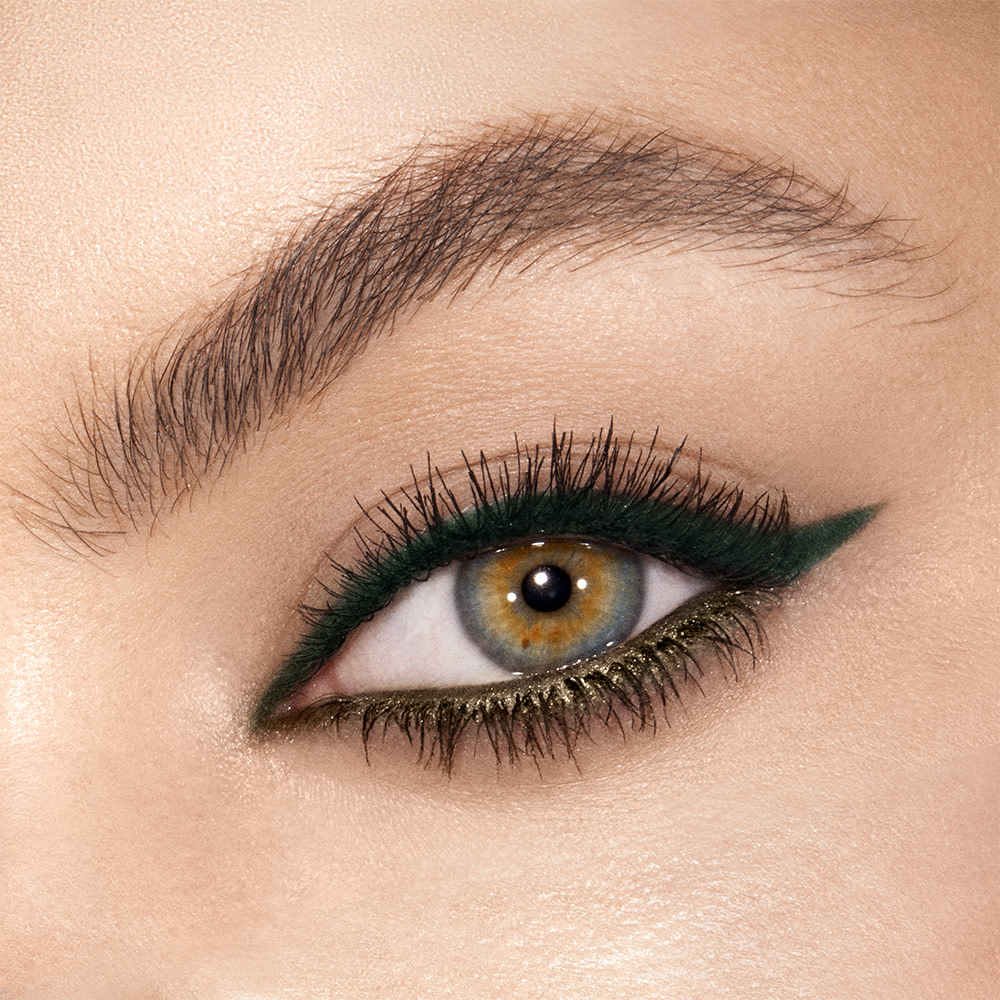Single-eye close-up of a model with hazel eyes wearing bottle green eyeliner on her eyelid and metallic khaki-coloured eyeliner on her lower waterline.