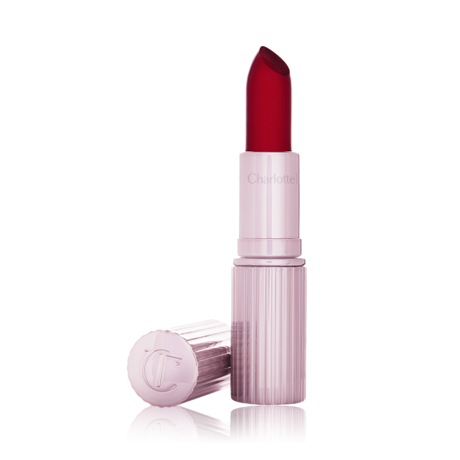 An open glowy, colour-changing lipstick in a sheer red colour with a luminous purple-coloured tube and lid. 