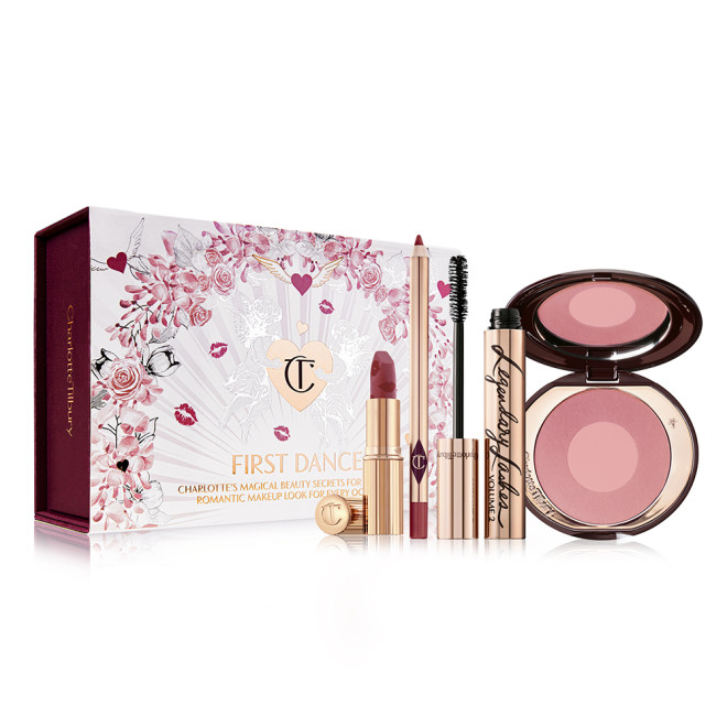 An open red lipstick with a red lip liner pencil, an open mascara in golden-coloured packaging, and an open two-tone blush in rose gold and warm pink with a white-coloured gift box with hearts and lipstick kiss prints all over with the text, 'Wedding Belles' written on the front. 
