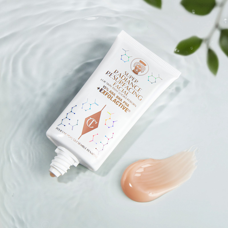 Un masque exfoliant chimique à rincer, présenté dans un tube blanc avec une inscription dorée, accompagné d’un swatch crémeux couleur brun champagne.