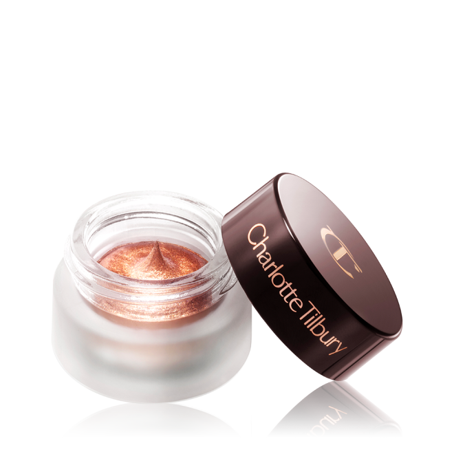 A coppery gold. cream eyeshadow in an open glass pot with a dark brown-coloured lid. 