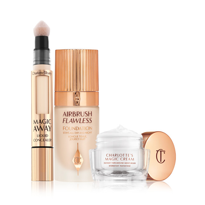 Creamy liquid concealer in a gold-coloured tube with a soft sponge applicator end, foundation in a frosted glass bottle with a gold-coloured lid, and pearly-white face cream in a glass jar with a gold coloured lid.