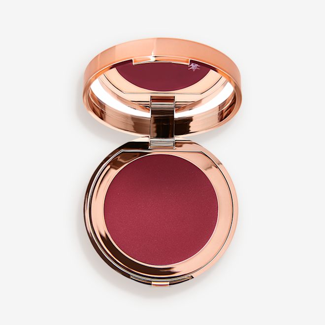 Pillow Talk Lip and Cheek Glow in Colour of Passion open An open, mirrored-lid lip and cheek cream compact in a berry-red shade.