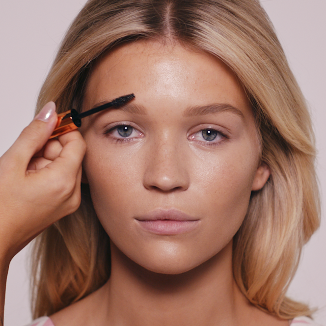 Fair blonde model with brow gel being applied to her eyebrows.