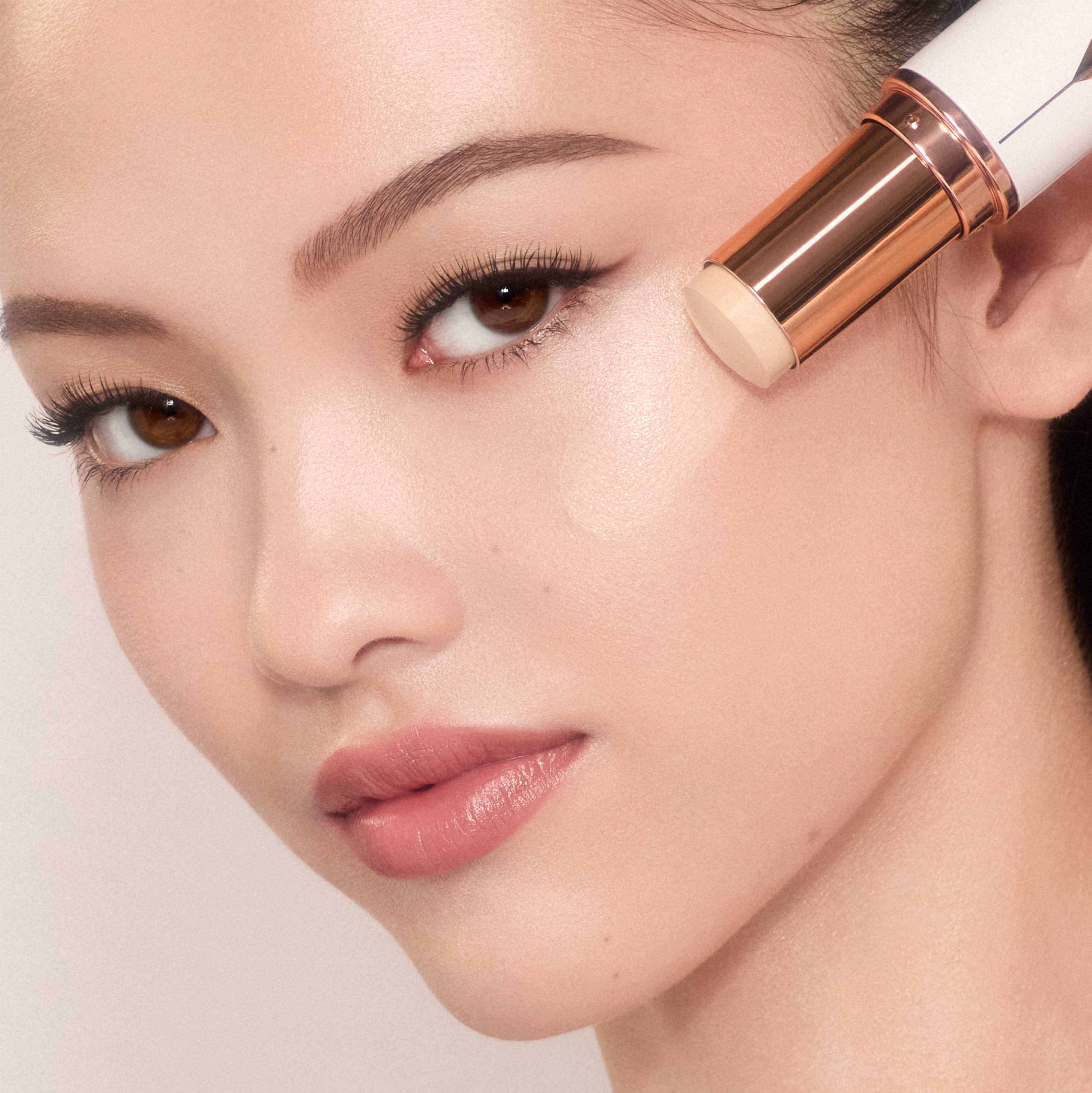 Mai-Li applying Charlotte's stick foundation Unreal Skin Sheer Glow Tint