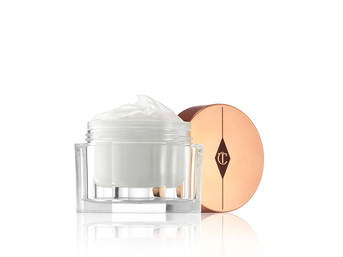 A thick, pearly-white face cream in a glass jar with a golden-coloured lid with the CT logo printed on it. 