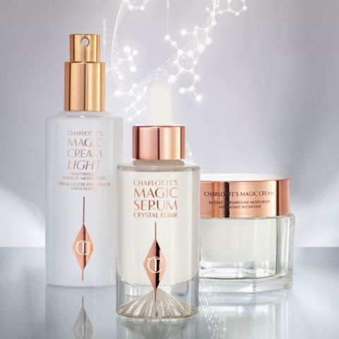 A light face cream in a transparent bottle with a pump dispenser, a luminous serum in a glass bottle, and a pearly-white face cream in a glass jar, all three in a white and gold colour scheme. 