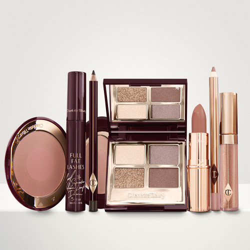 An open, mirrored-lid eyeshadow palette in matte and shimmery gold, brown, and beige shades, an open black eyeliner pencil, a mascara in a dark-crimson colour scheme, a golden-peach lipstick with a matching lip liner pencil, nude-peach lip gloss, and an open two-tone blush in muted brown-pink. 