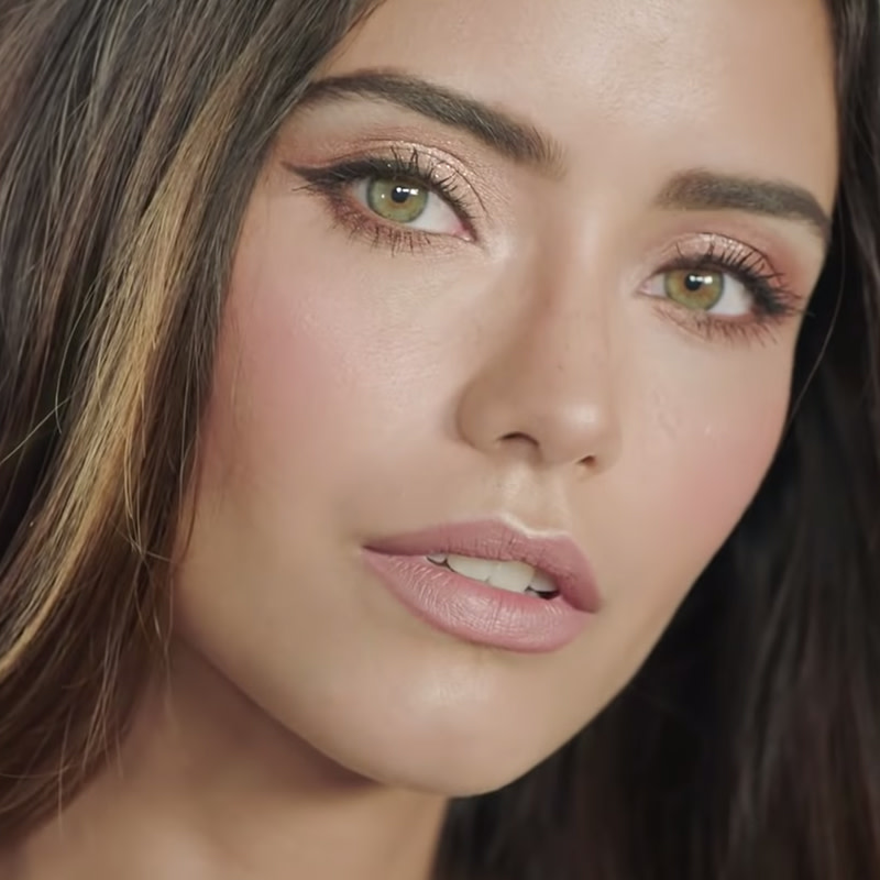 A light-tone model with green eyes wearing a soft and glowy champagne and nude pink makeup look that's perfect for a summer wedding. 