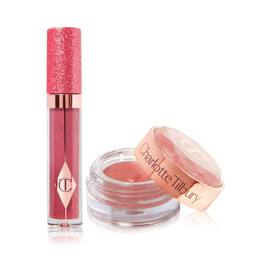 A shimmery berry-pink lip gloss in a glass tube with a glittery lid next to shimmery, cream eyeshadow in a berry-pink shade in a glass pot with its lid removed.