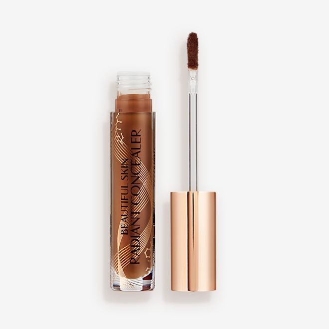 Beautiful Skin concealer in 16.5 open Dark brown radiant concealer in a glass tube with its gold-coloured lid with a doe-foot end next to it, and text on the tube that reads, 'Beautiful Skin Concealer'