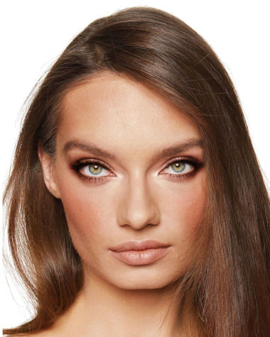 Medium-light-tone model with green eyes wearing nude peach lipstick with soft coral blush, shimmery rose gold eyeshadow, and glow bronzer.