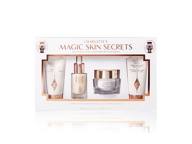 Pearly-white face cream in a glass jar with gold-coloured lid, luminous face serum in a glass bottle with a white and gold-coloured dropper lid, and a clay mask and glowy primer in white-coloured bottles with gold-coloured lids, all packed in a white-coloured box. 