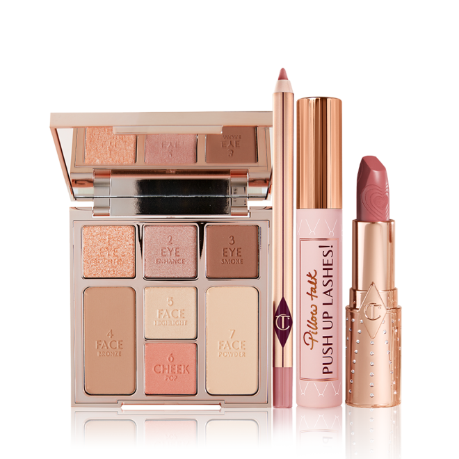 An open, mirrored-lid face palette with nude eyeshadows, nude pink and soft pink blushes, bronzer, and highlighter, an open lip liner pencil in nude pink shade, black mascara with nude pink tube with a gold-coloured lid, and an open lipstick in a nude pink shade in a gold-coloured tube. 