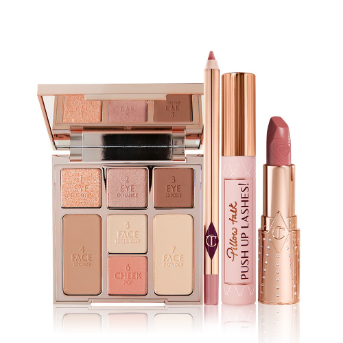 An open, mirrored-lid face palette with nude eyeshadows, nude pink and soft pink blushes, bronzer, and highlighter, an open lip liner pencil in nude pink shade, black mascara with nude pink tube with a gold-coloured lid, and an open lipstick in a nude pink shade in a gold-coloured tube. 