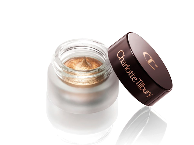 An open pot of cream eyeshadow in a rich, burnished, amber-gold shade with the lid next to it. 