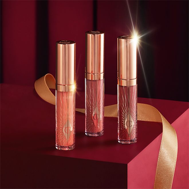 Mini Collagen Lip Bath Trio closed Three lip glosses in shades of light pink, coral-peach, and brown-pink in glass tubes with gold-coloured lids.