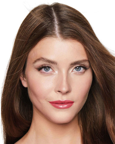 Fair-tone model with blue eyes wearing shimmery champagne eyeshadow with black eyeliner, and high-shine, berry-pink tinted lip oil 