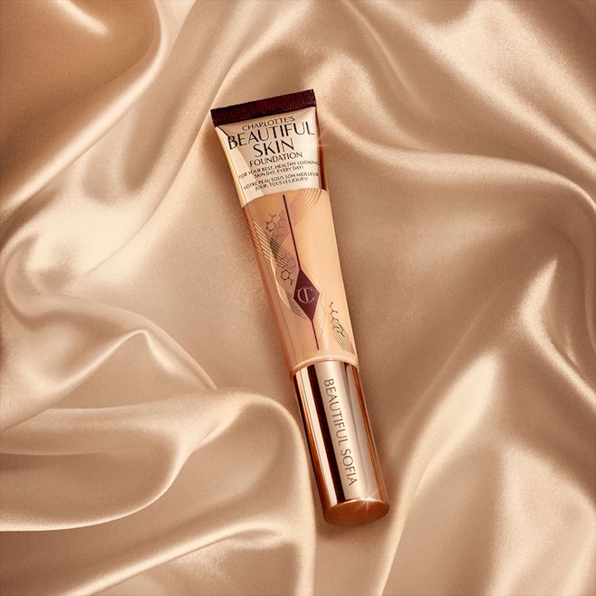 Beautiful Skin Foundation engraved tube for medium-tone A foundation wand in gold packaging with a brown-beige-coloured body to show the shade of the foundation inside, and a gold-coloured lid.