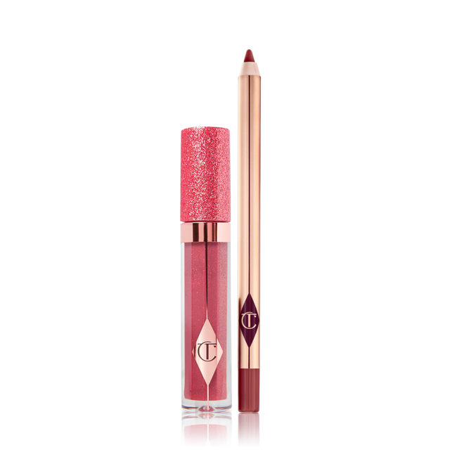 Shimmery lip gloss in a berry-pink shade in a glass tube with a glittery lid with an open lip liner pencil in a dark berry-pink shade. 